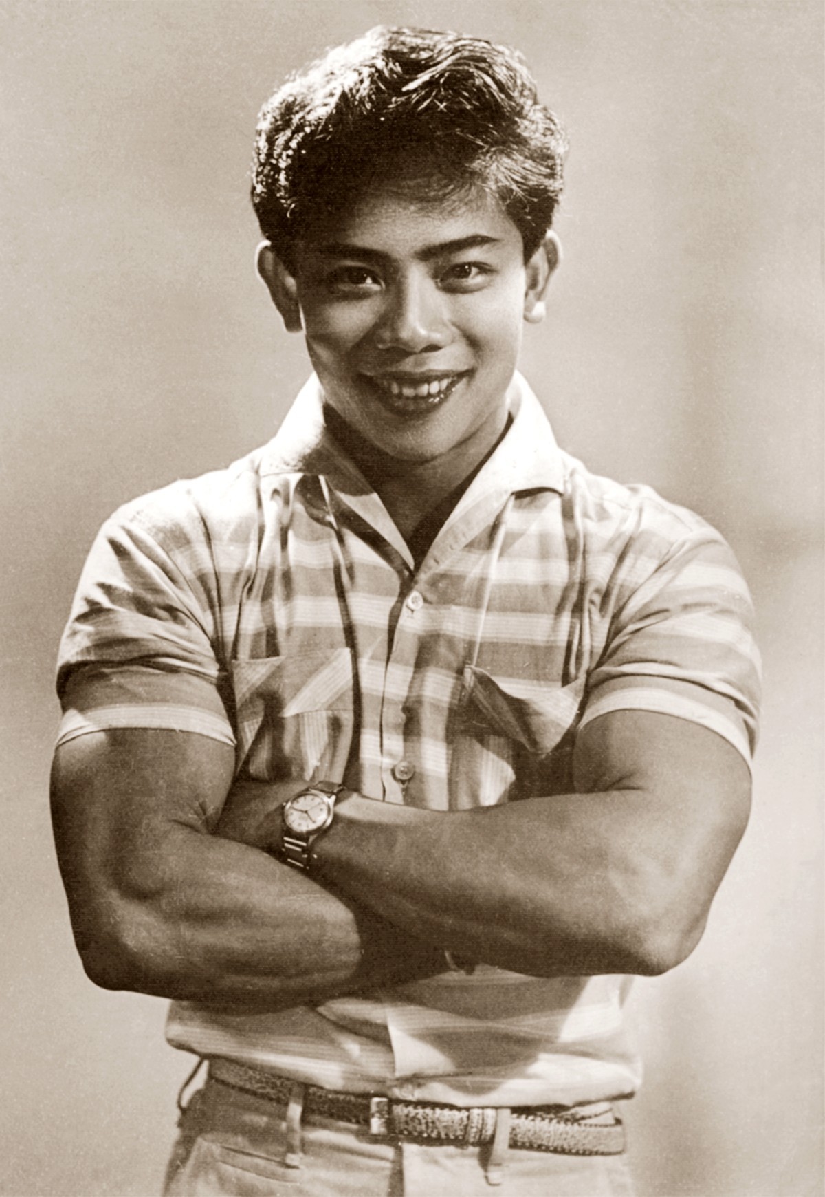 An old black and white photograph of a muscular Vietnamese man with his arms folded